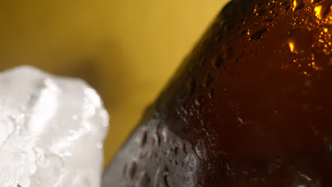 Nahaufnahme-Einer-Person,-Die-Eine-Gekühlte-Glasflasche-Kaltes-Bier-Oder-Alkoholfreie-Getränke-Aus-Einem-Mit-Eis-Gefüllten-Eimer-Vor-Gelbem-Hintergrund-Nimmt-3